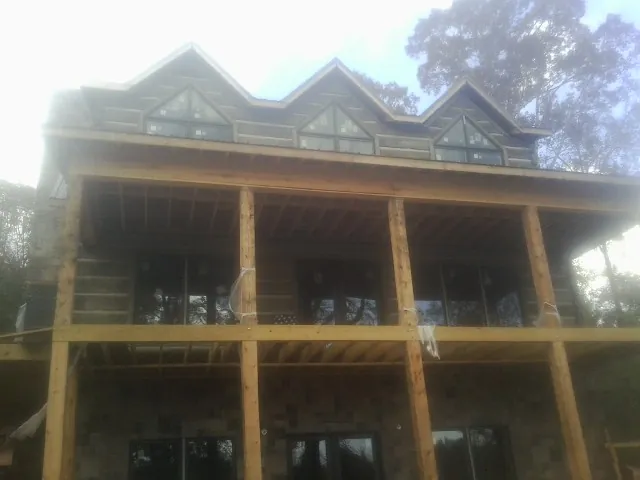 Dormers and porch framing on a large log home under construction — Roof Coating work by our crew in Marshall