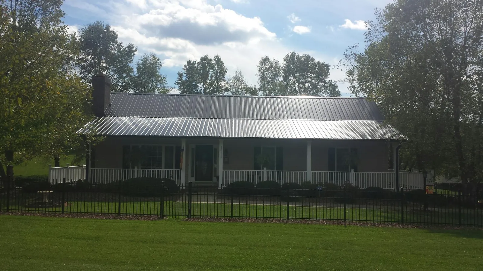 Gray metal roof on a brick ranch with a full width front porch — Gutter Guard Installation work by our crew in Marshall